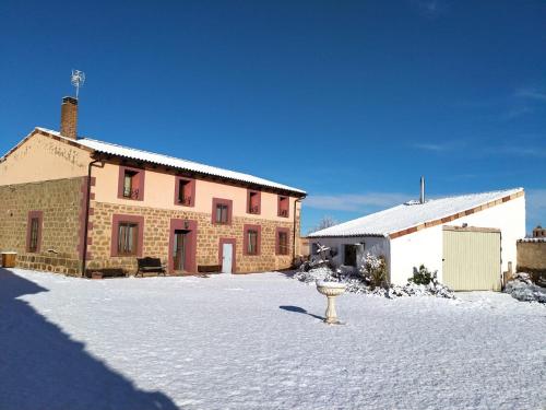 a house in the snow next to a building at Hotel Rural El Cielo Entejado 