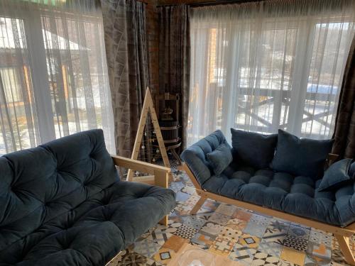 a living room with two blue couches and large windows at BrickWood in Verkhniy Koropets