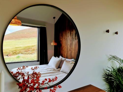 a mirror in a bedroom with a bed and a window at Svartaborg in Húsavík