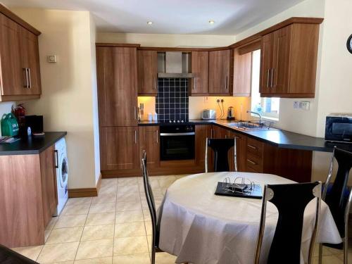 uma cozinha com armários de madeira e uma mesa com uma toalha de mesa branca em Charlies Lane Apartment em Donegal