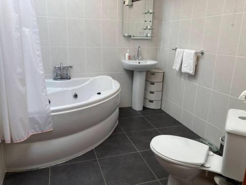 a bathroom with a tub and a toilet and a sink at Charlies Lane Apartment in Donegal