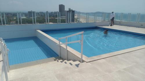 a man standing in a swimming pool on top of a building at Frente pro mar apartamento completo in Praia Grande