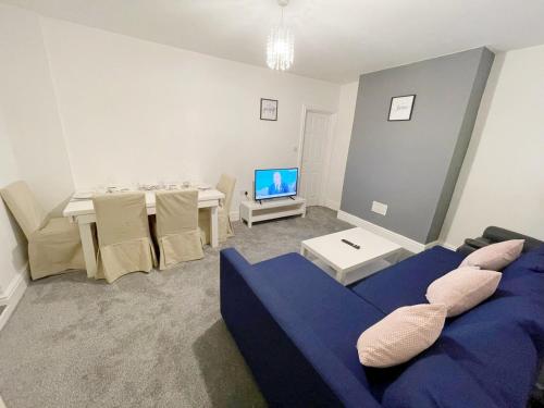 a living room with a blue couch and a table at New Brighton Flat in Wallasey