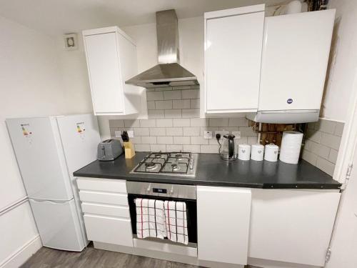 uma cozinha com armários brancos e um forno com placa de fogão em New Brighton Flat em Wallasey