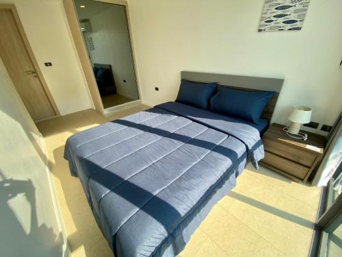 a bedroom with a bed with blue sheets and a mirror at Sea Zen Condominium Bang Saray in Bang Sare