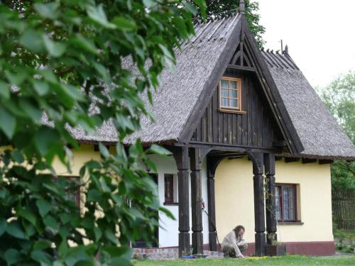 a woman sitting in front of a small house at Chata pod klonami in Dziemiany