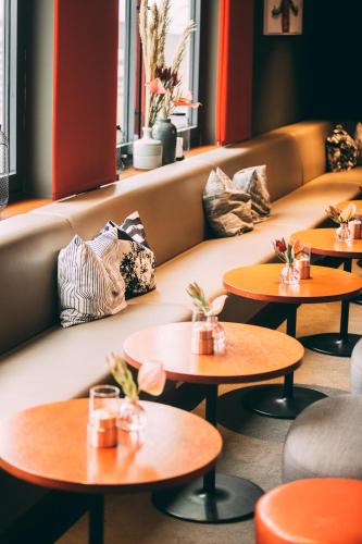 a row of tables in a restaurant with a couch at Me and All Hotel Dusseldorf, by Hyatt in Düsseldorf