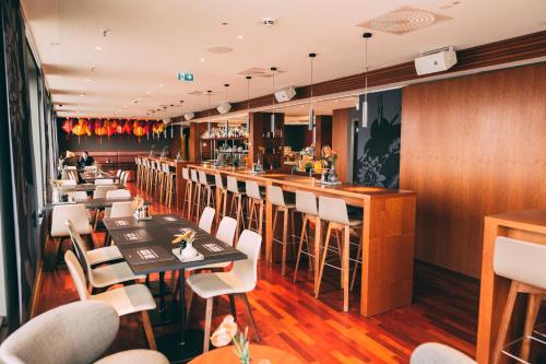 a restaurant with tables and chairs and a bar at Me and All Hotel Dusseldorf, by Hyatt in Düsseldorf