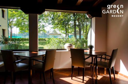 een restaurant met 2 tafels en stoelen en een groot raam bij GREEN GARDEN Resort - Smart Hotel in Mestre