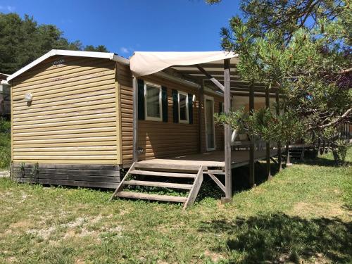 Ce chalet en bois dispose d'une véranda et d'une terrasse. dans l'établissement Camping le Lac, à Le Villard