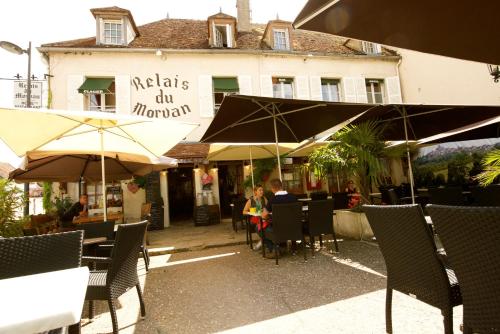 Eine Frau, die an einem Tisch vor einem Gebäude sitzt. in der Unterkunft Le Relais du Morvan in Vézelay