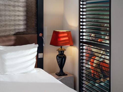 - une chambre avec un lit et une lampe rouge dans l'établissement The Dominican, Brussels, a Member of Design Hotels, à Bruxelles