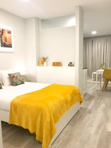 a bedroom with a bed with a yellow blanket on it at Domus da Ria - Teatro in Aveiro