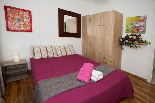 ein Schlafzimmer mit einem lila Bett und einem Schrank in der Unterkunft Nefeli Sea Side, Boutique Apartment in Limassol