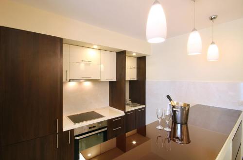 a kitchen with white cabinets and a table with wine glasses at Shine residence in Budva