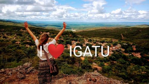 a woman standing on top of a mountain with her arms up at CASA TRILHAS DE IGATU - CHAPADA DIAMANTINA - BAHIA in Igatu