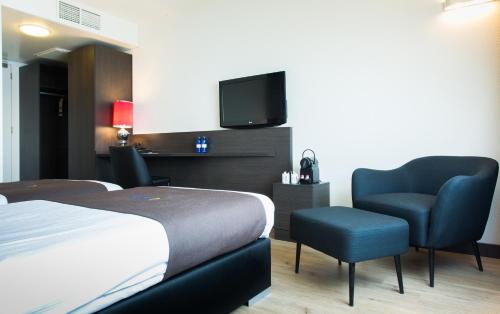 a hotel room with a bed and a chair and a tv at Bastion Hotel Amsterdam Amstel in Amsterdam