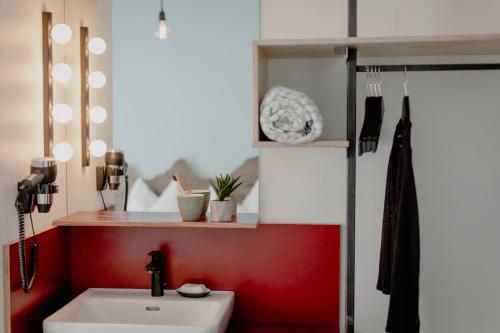 a bathroom with a white sink and a red wall at Bett & Berg Bad Ischl, Self Check-In in Bad Ischl