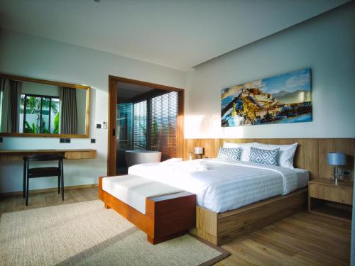 a bedroom with a large bed and a desk and window at Bliss Villa at Shambhala Grand in Bang Tao Beach