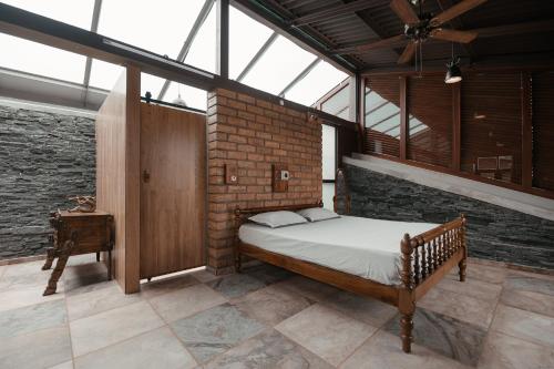 a bedroom with a bed and a brick wall at RainTree EcoStay in Māranhalli