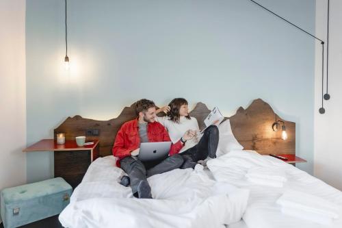 a man and woman sitting on a bed with a laptop at Bett & Berg Bad Ischl, Self Check-In in Bad Ischl