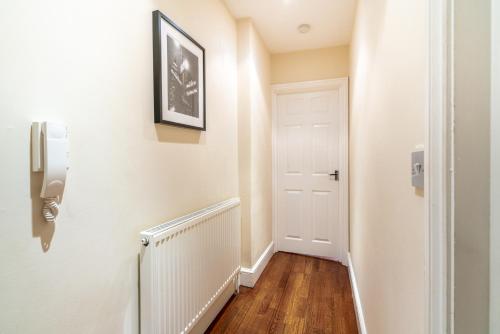 a hallway with a white door and wooden floors at One Bedroom Flat in Bush Hill Park in Enfield
