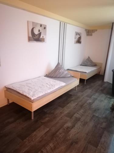 two beds in a room with wooden floors at Tinas Ferienwohnung in Hohendodeleben