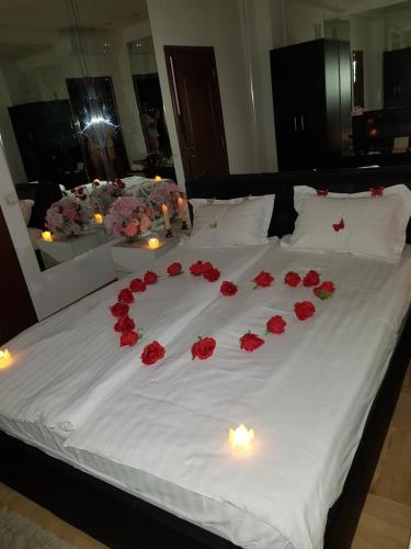 a bed with red roses and candles on it at Mirrors Room Mega Mall National Arena in Bucharest