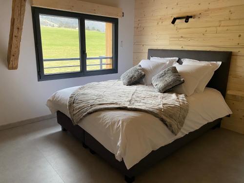 um quarto com uma cama com almofadas e uma janela em Gîte de charme avec jacuzzi #Calme #Cosy em Viuz-en-Sallaz
