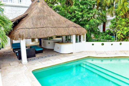 una gran piscina con una sombrilla de paja y una piscina en tropical en Playa del Carmen