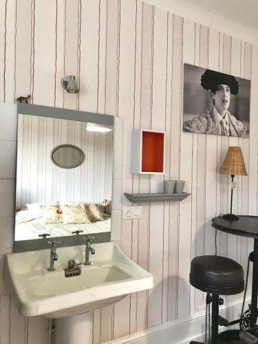 La salle de bains est pourvue d'un lavabo, d'un miroir et d'un tabouret. dans l'établissement Le Grand Dehors 01, à Cerdon