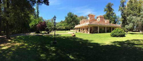 a woman is standing in front of a large house at Estancia Don Pedro in San Antonio de Areco