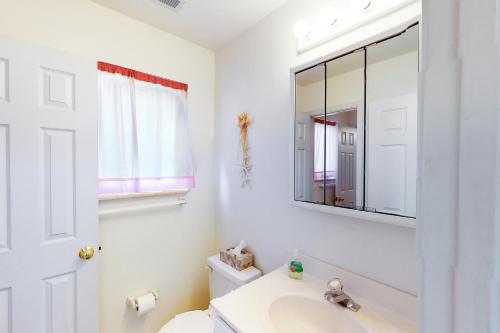 a white bathroom with a sink and a mirror at Captain's Deck in Ocean City