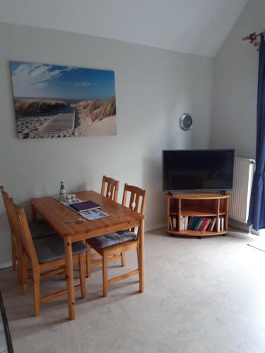 a dining room with a table and chairs and a television at Ferienwohnung Wattwurm Dangast in Varel