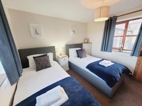 a bedroom with two beds and a window at Grosmont Cottage, Ruswarp in Whitby