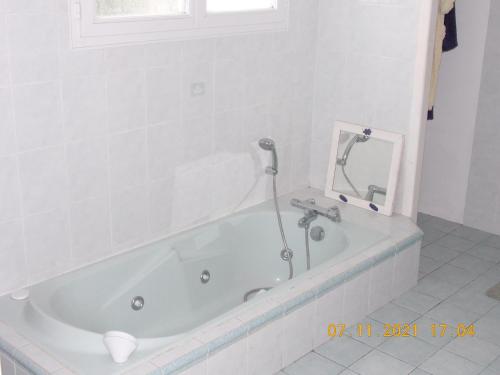 y baño con bañera y espejo. en Maison de 3 chambres avec jacuzzi jardin amenage et wifi a Angoume, en Angoumé