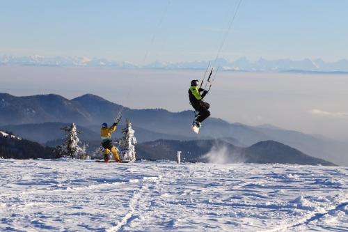 two people are jumping in the air in the snow at Hôtel Restaurant Wolf in Markstein 