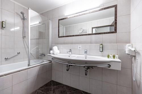 a bathroom with a sink and a tub and a mirror at Hotel Pirchnerhof in Reith im Alpbachtal