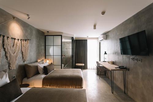 a bedroom with a bed and a desk and a television at Glory Wabi Sabi Hotel清迈古城荣耀侘寂酒店 in Chiang Mai