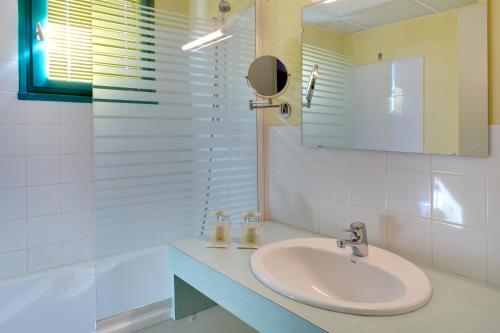 a white bathroom with a sink and a mirror at Logis L'Auberge Bourbonnaise in Saint-Yorre