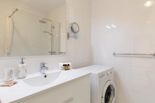 a white bathroom with a washing machine and a sink at Le Minerve YourHostHelper in Cannes