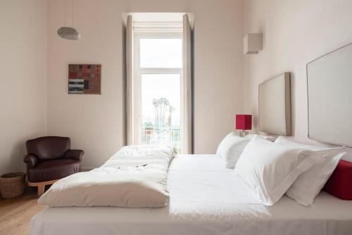 Un dormitorio blanco con 2 camas y una silla en Micalò Art Rooms en Nápoles