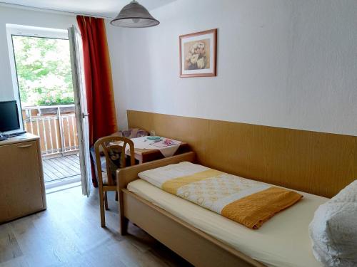a small bedroom with a bed and a small table at Pension Schneider, Bad Gögging in Neustadt an der Donau