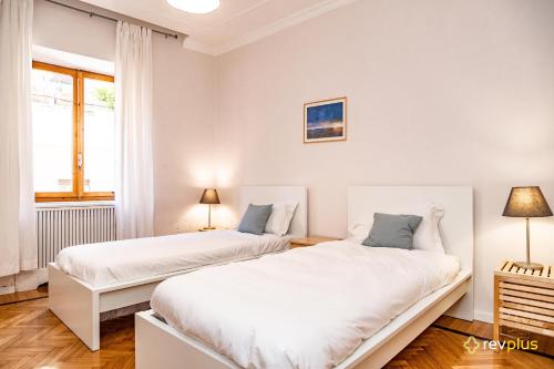 2 camas en una habitación blanca con ventana en Mecenate Apartment Fori Imperiali, en Roma