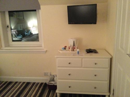 a bedroom with a dresser and a television on the wall at Dawn Break Guest House in Largs