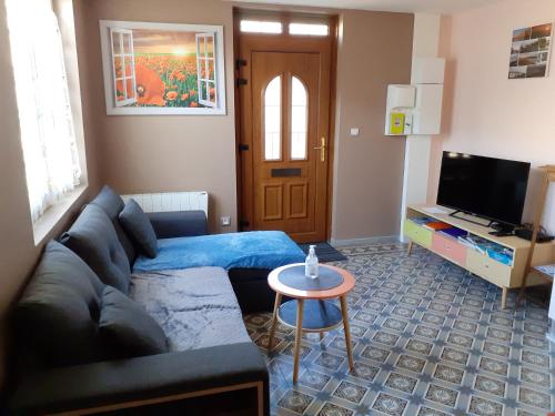 a living room with a couch and a table at Maison charmante à Saint-Blimont avec jardin in Saint-Blimont