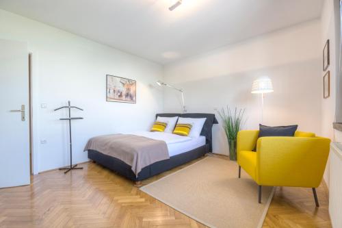 ein Schlafzimmer mit einem Bett und einem gelben Stuhl in der Unterkunft Apartments Fine Ziherlova in Ljubljana