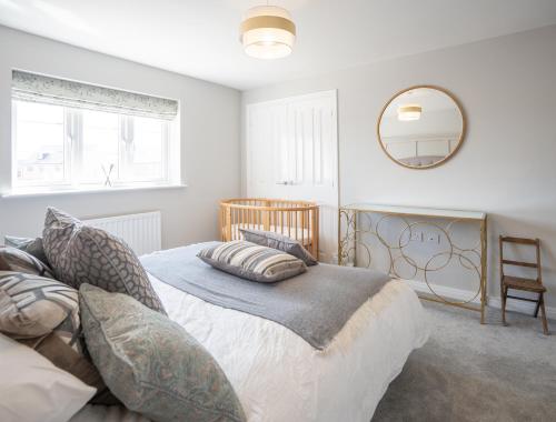 a bedroom with a bed with pillows and a mirror at Immaculate 4-Bed House 5mins walk to Village shop in Bicester