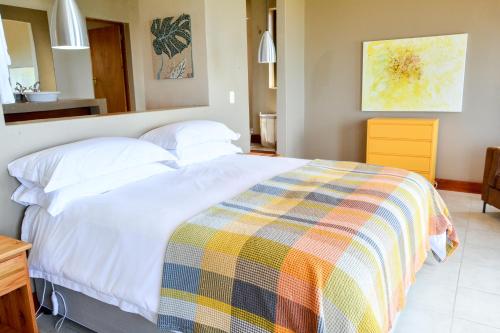 a bedroom with a white bed with a colorful blanket at 4 Zwaan in Jeffreys Bay