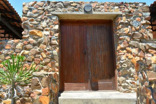 a stone building with a wooden door on it at 4 Zwaan in Jeffreys Bay